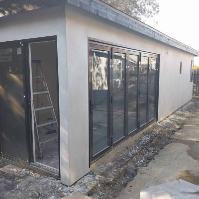 Modern home construction with energy-efficient glass sliding doors and stucco exterior, showcasing professional residential renovation and building services by Andromeda Construction Inc.
