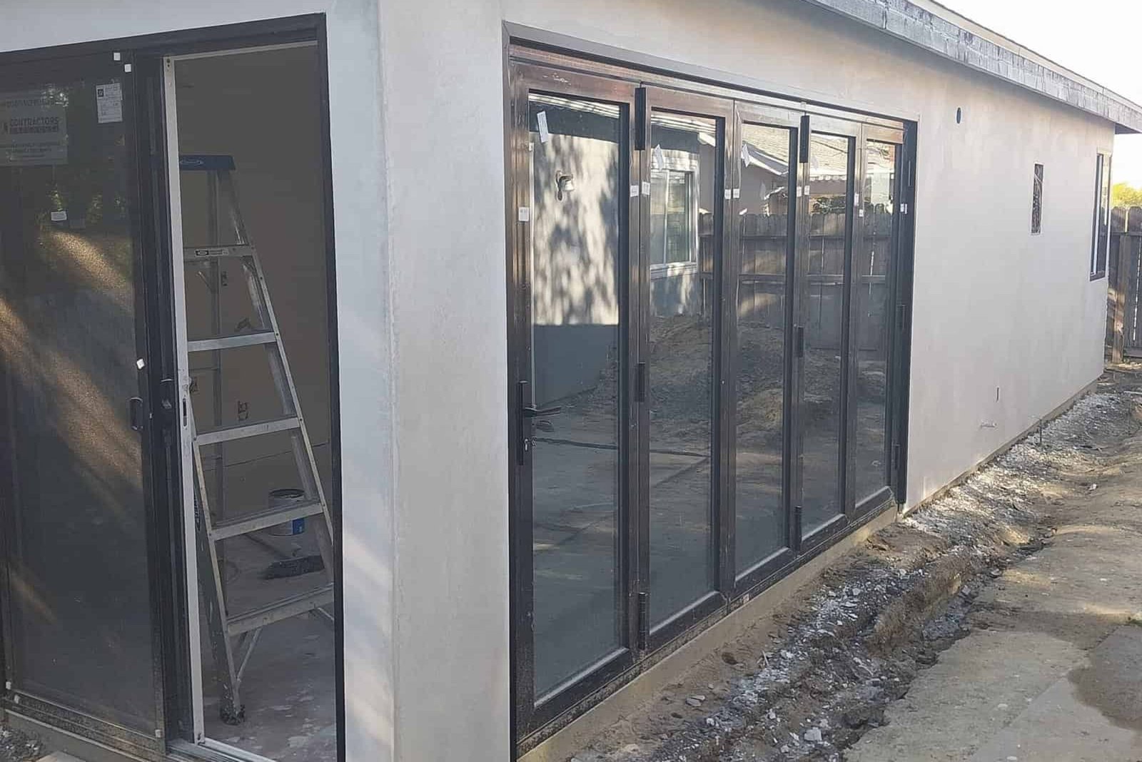 Modern home construction with energy-efficient glass sliding doors and stucco exterior, showcasing professional residential renovation and building services by Andromeda Construction Inc.