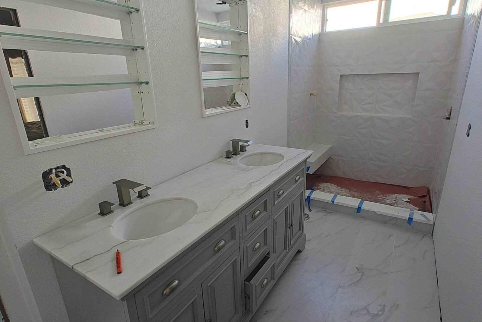 Ofrece una vista moderna de un baño en construcción con diseño elegante y acabados en mármol, ideal para proyectos de construcción y remodelación residencial y comercial.
