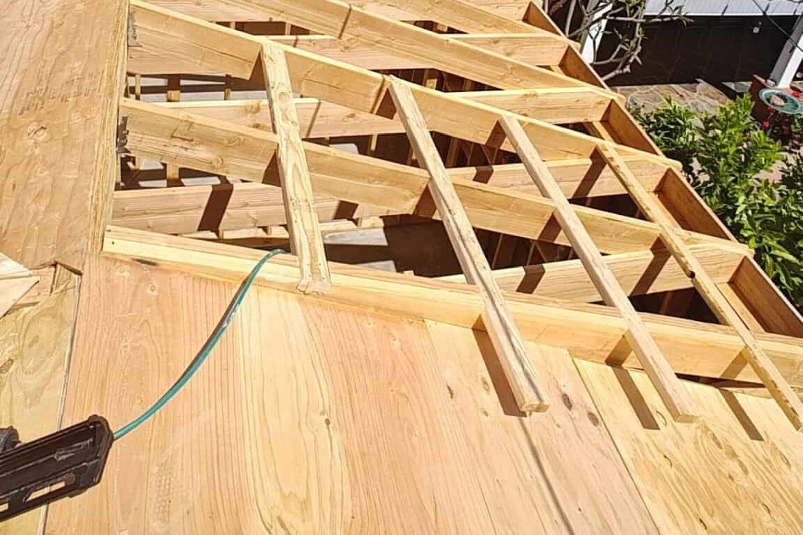 Cubierta de madera en construcción, estructura de techos en proceso con madera tratada y herramientas de carpintería en uso, especializado en construcción de techos y remodelaciones de viviendas.