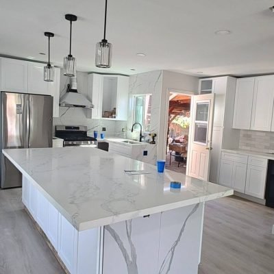 Puerta de cocina moderna y luminosa con encimeras de cuarzo blanco de veta gris. Diseño elegante en residencia de construcción con estilo contemporáneo y acabados de alta calidad.